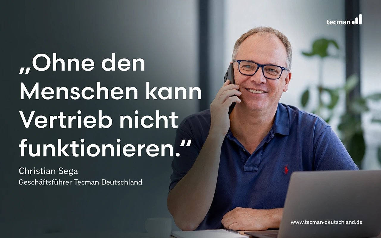 Christian Sega, Geschäftsführer von Tecman Deutschland, telefoniert am Schreibtisch neben einem Laptop – mit dem Zitat: Ohne den Menschen kann Vertrieb nicht funktionieren.